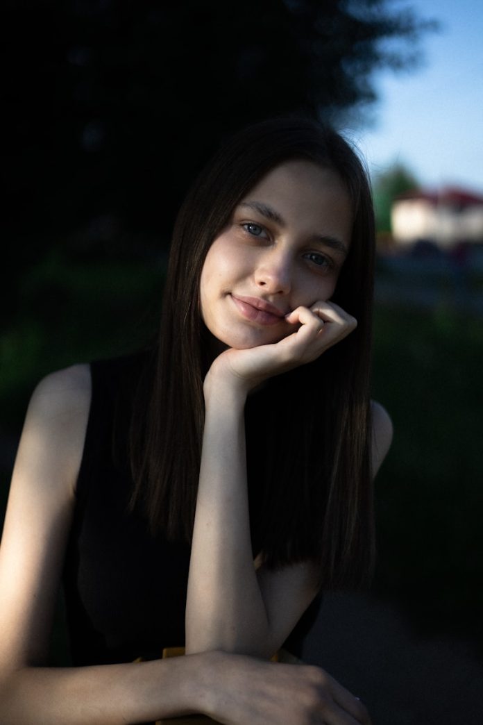 A young woman poses with her hand on chin.