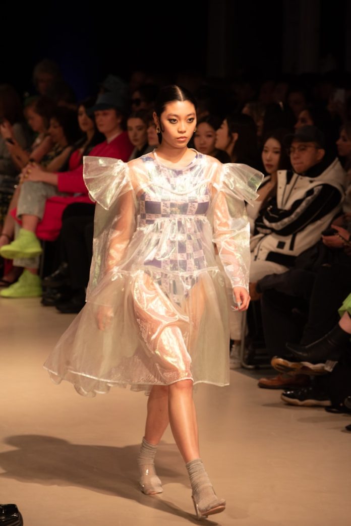 a woman walking down a runway in a dress