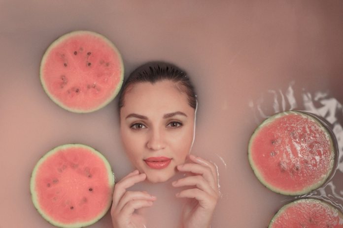 a woman in a bubble bath with slices of watermelon