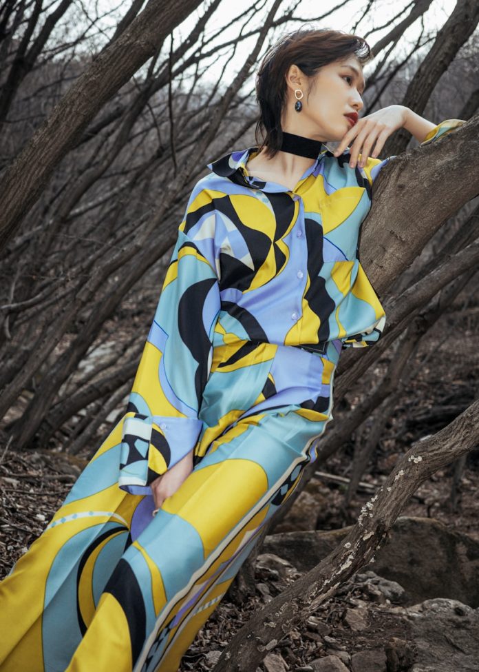 a woman sitting on a tree trunk in a colorful dress